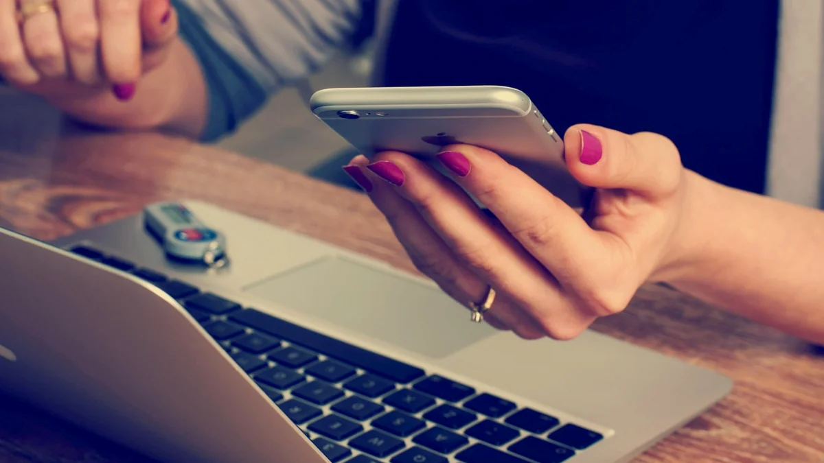 Person nutzt Smartphone und Laptop als Symbol für eine bewusste Cloud-Entscheidung im Familienalltag